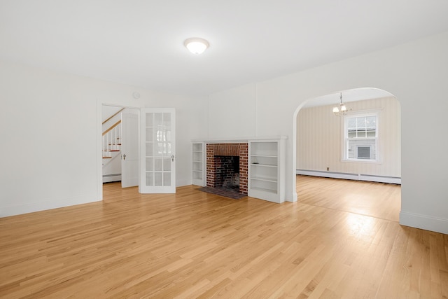 606 Main St, Sanford, ME 04083 - unfurnished living room with a baseboard radiator, arched walkways, light wood finished floors, a chandelier, and stairway