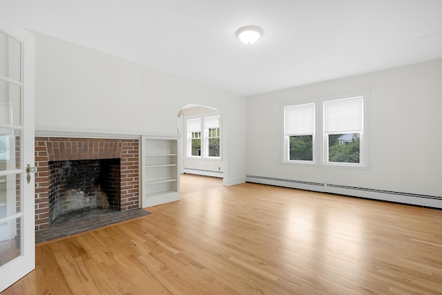 606 Main St, Sanford, ME 04083 - unfurnished living room with a baseboard heating unit, baseboard heating, wood finished floors, arched walkways, and a brick fireplace
