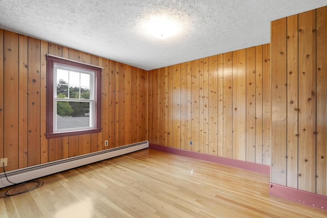 606 Main St, Sanford, ME 04083 - empty room featuring a baseboard heating unit, wood finished floors, a textured ceiling, and wooden walls