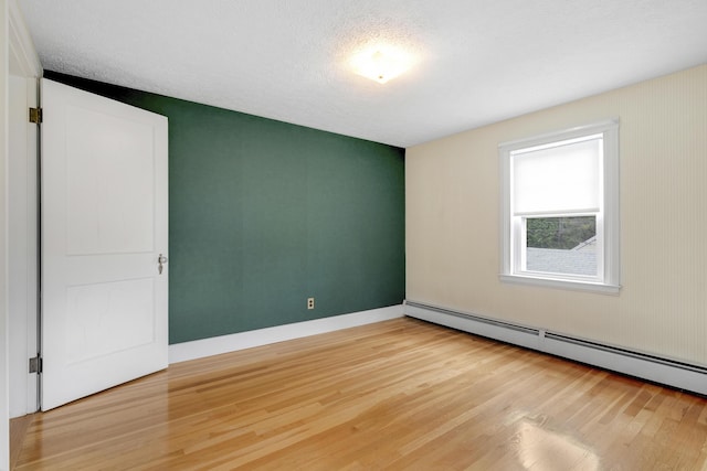 606 Main St, Sanford, ME 04083 - unfurnished room with baseboard heating, light wood finished floors, a textured ceiling, and baseboards