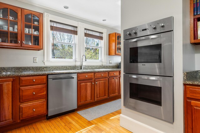 11 Summer St, Kennebunk, ME 04043 - kitchen featuring appliances with stainless steel finishes, light wood-type flooring, glass insert cabinets, brown cabinetry, and a sink