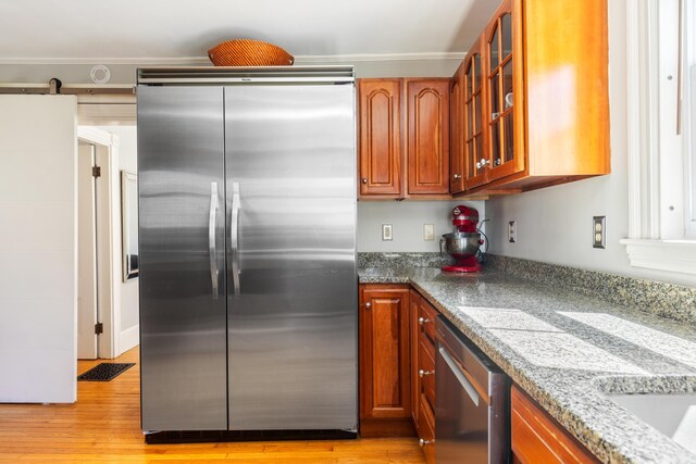 11 Summer St, Kennebunk, ME 04043 - kitchen with stainless steel appliances, glass insert cabinets, light wood finished floors, crown molding, and brown cabinets
