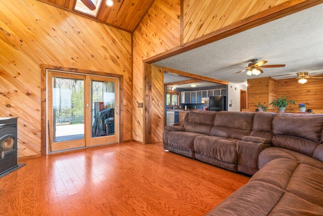 414 Oak Hill Rd, Litchfield, ME 04350 - living area with wooden walls, a wood stove, wood finished floors, ceiling fan, and a skylight