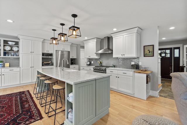 16 Sweet Fern Ln, Bowdoinham, ME 04008 - kitchen with wall chimney range hood, premium appliances, tasteful backsplash, a breakfast bar, and light wood-style floors