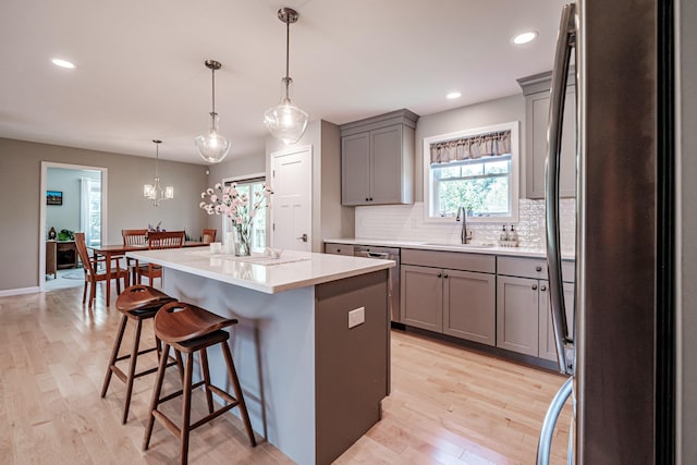 48 Sancho Dr, Saco, ME 04072 - kitchen featuring stainless steel appliances, gray cabinetry, a sink, a kitchen island, and a kitchen bar