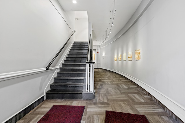 staircase with carpet floors and track lighting