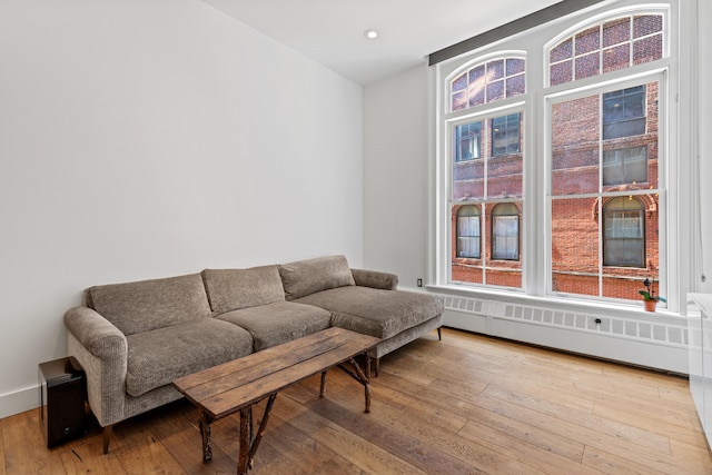 living room featuring radiator, hardwood / wood-style floors, and recessed lighting