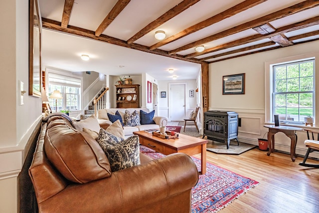 71 Brook Rd, Falmouth, ME 04105 - living room with healthy amount of natural light, stairs, a wood stove, light wood-style floors, and beamed ceiling