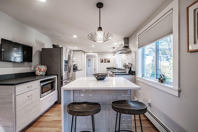 28 Stone Dr, Cape Elizabeth, ME 04107 - kitchen with stainless steel microwave, wall chimney range hood, a breakfast bar area, light wood-style floors, and white cabinets