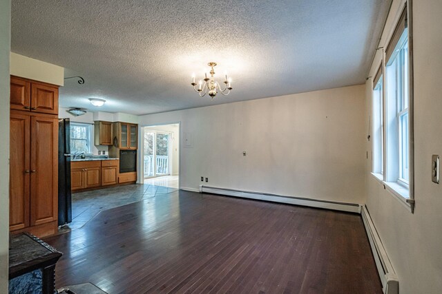 55 Reservoir Rd, Paris, ME 04281 - unfurnished living room with dark wood finished floors, a chandelier, a textured ceiling, baseboard heating, and baseboards