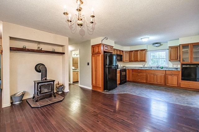 55 Reservoir Rd, Paris, ME 04281 - kitchen with black appliances, brown cabinetry, a textured ceiling, a chandelier, and a wood stove