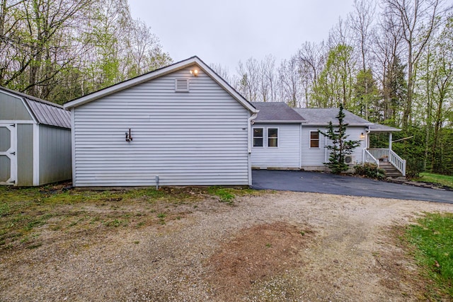 55 Reservoir Rd, Paris, ME 04281 - rear view of property featuring a storage unit, an outdoor structure, roof with shingles, and driveway