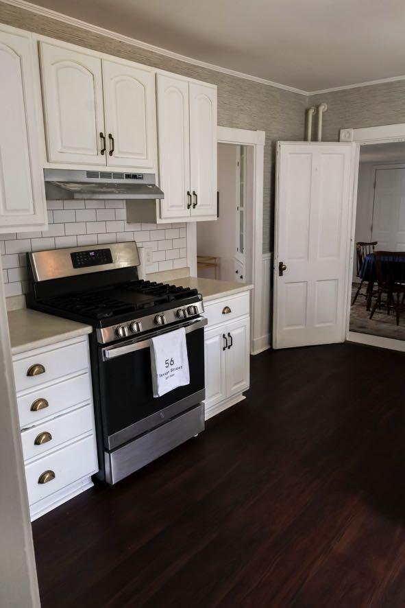 56 Savage St, Bangor, ME 04401 - kitchen with stainless steel gas range oven, under cabinet range hood, white cabinets, light countertops, and dark wood-type flooring