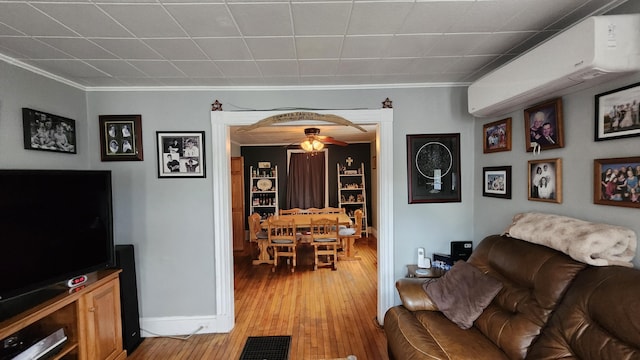 295 Grove St, Bangor, ME 04401 - living room featuring light wood-type flooring, crown molding, a wall mounted air conditioner, and baseboards