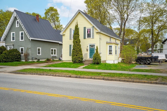 192 Wilson St, Brewer, ME 04412 - view of front facade featuring a chimney, entry steps, metal roof, and a front lawn