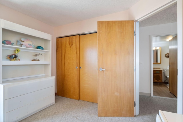 205 E Grand Ave Unit 7E, Old Orchard Beach, ME 04064 - bedroom with light colored carpet, a closet, a textured ceiling, and ensuite bath