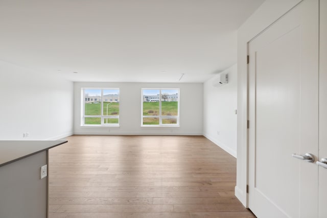 218 Washington Ave Unit 309, Portland, ME 04101 - empty room with light wood finished floors, a wall unit AC, and baseboards