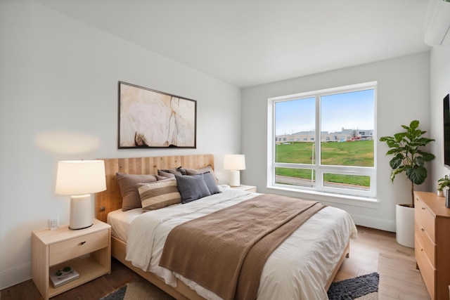 218 Washington Ave Unit 309, Portland, ME 04101 - bedroom featuring an AC wall unit, light wood finished floors, and baseboards