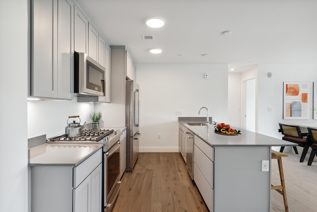 218 Washington Ave Unit 309, Portland, ME 04101 - kitchen with appliances with stainless steel finishes, a peninsula, a kitchen bar, light wood-type flooring, and a sink