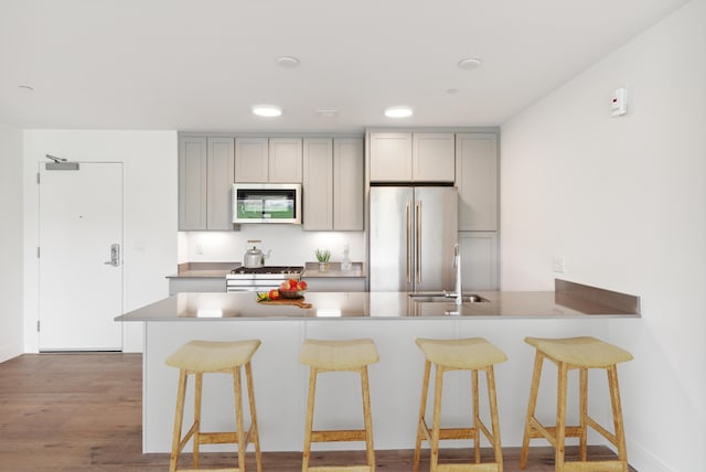 218 Washington Ave Unit 309, Portland, ME 04101 - kitchen featuring appliances with stainless steel finishes, gray cabinets, a sink, a kitchen breakfast bar, and recessed lighting