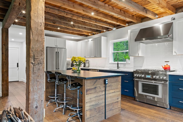 6 Bluebird Way, Kennebunk, ME 04043 - kitchen featuring high end appliances, wood-type flooring, wall chimney exhaust hood, decorative backsplash, and wooden ceiling with exposed beams