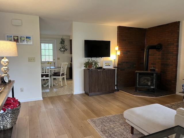 living area with light wood-style floors, baseboards, and a wood stove