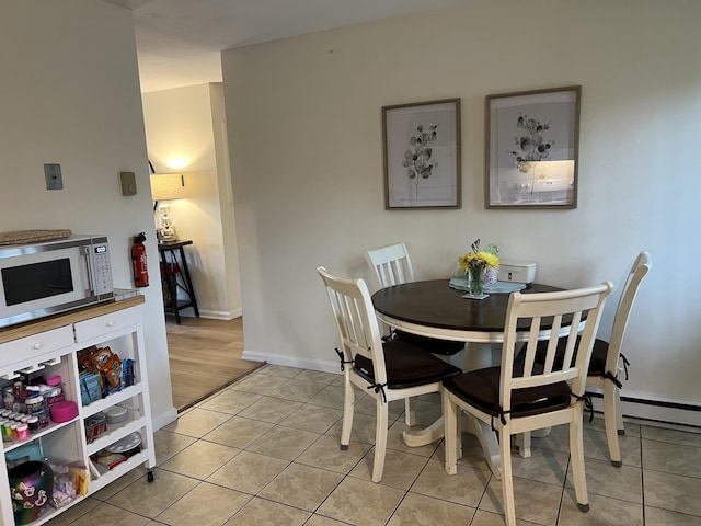 dining room featuring light tile patterned floors, baseboards, and baseboard heating