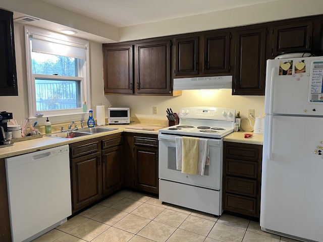 kitchen featuring white appliances, under cabinet range hood, a sink, and light tile patterned flooring