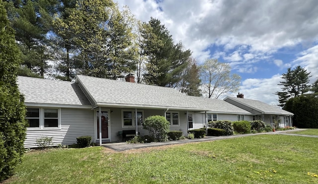 ranch-style home with a chimney, a front lawn, roof with shingles, and a porch