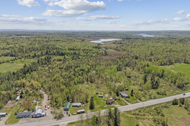 aerial view of property and surrounding area with a forest and a nearby body of water