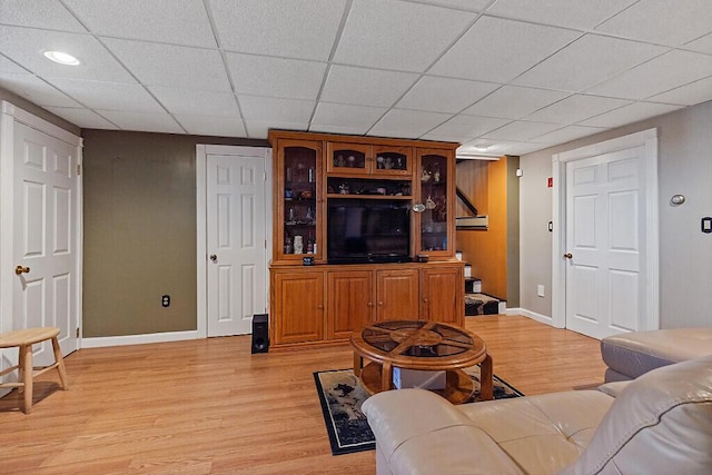 living area with baseboards, light wood-style floors, and a paneled ceiling