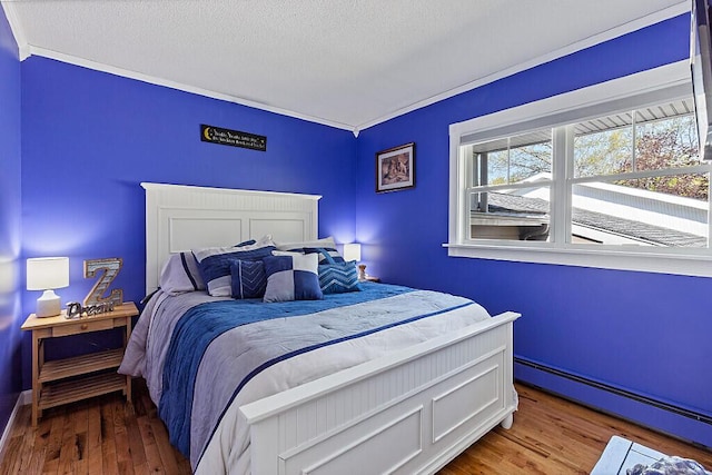 bedroom featuring a baseboard radiator, wood finished floors, and a textured ceiling