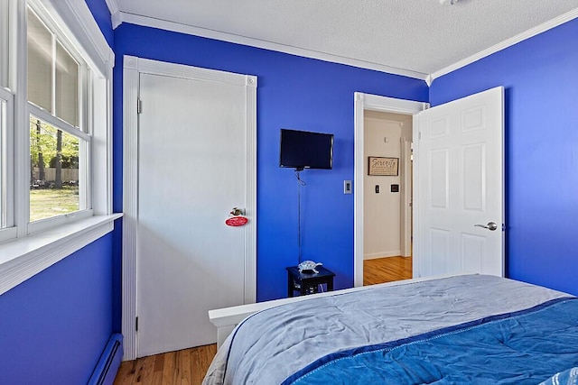 bedroom featuring wood finished floors, crown molding, baseboards, a closet, and a textured ceiling