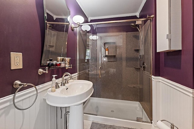 bathroom featuring ornamental molding, a shower stall, and a wainscoted wall