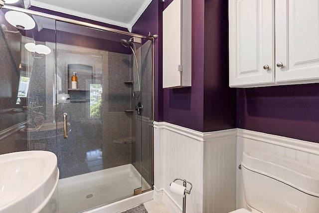 full bathroom with crown molding, wainscoting, a shower stall, toilet, and a sink