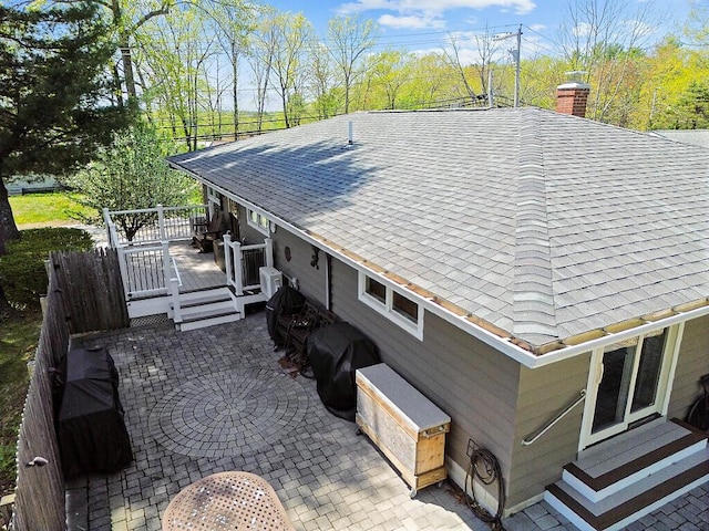 view of side of home featuring a shingled roof, a wooden deck, and a chimney