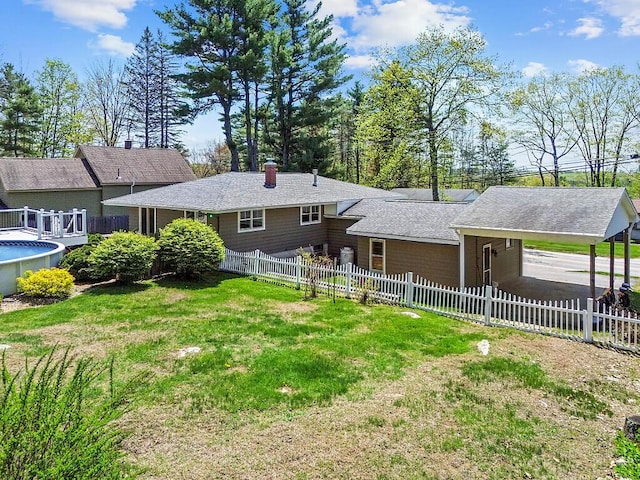 rear view of property with a chimney, an outdoor pool, and a carport