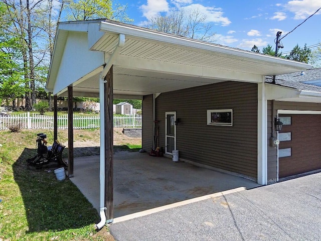 view of vehicle parking featuring fence and a carport