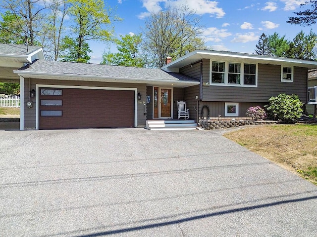 view of front facade with asphalt driveway, an attached garage, and a chimney