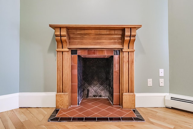 detailed view of a tile fireplace, wood finished floors, and baseboard heating