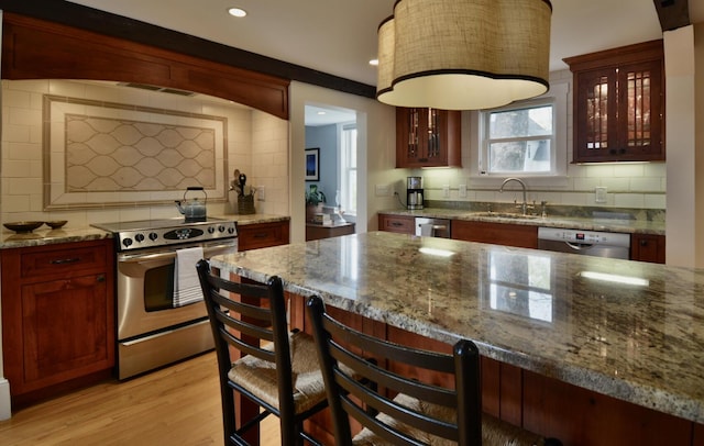 131 N St, Bath, ME 04530 - kitchen featuring stainless steel appliances, a sink, decorative backsplash, light wood-style floors, and a kitchen bar