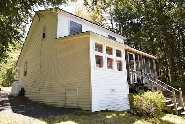 view of side of property with a sunroom and stairs