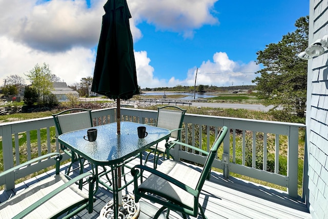 wooden terrace featuring outdoor dining space and a water view