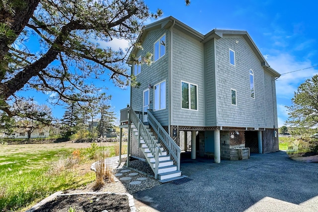 rear view of property featuring a carport, stairs, and driveway