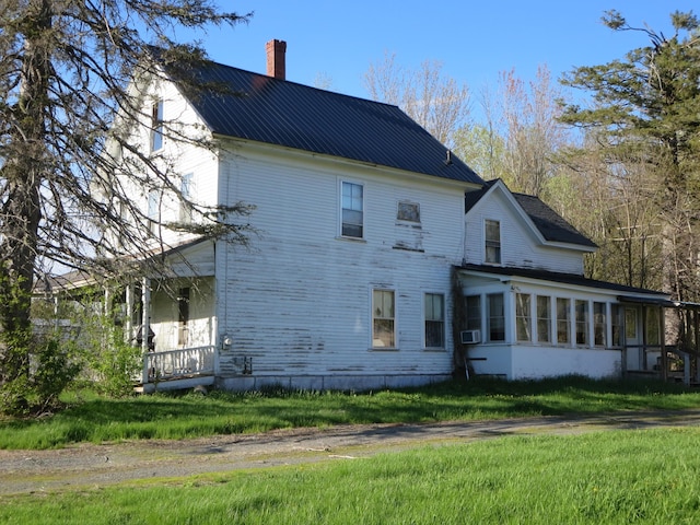 rear view of property with a chimney, a sunroom, metal roof, a yard, and cooling unit