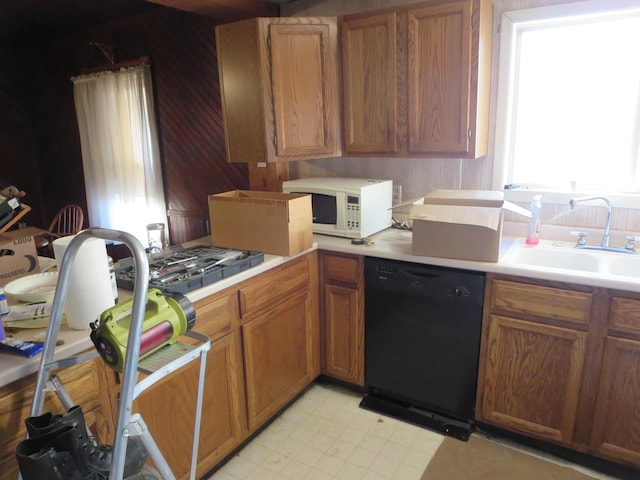 kitchen featuring dishwasher, white microwave, a sink, light countertops, and light flooring