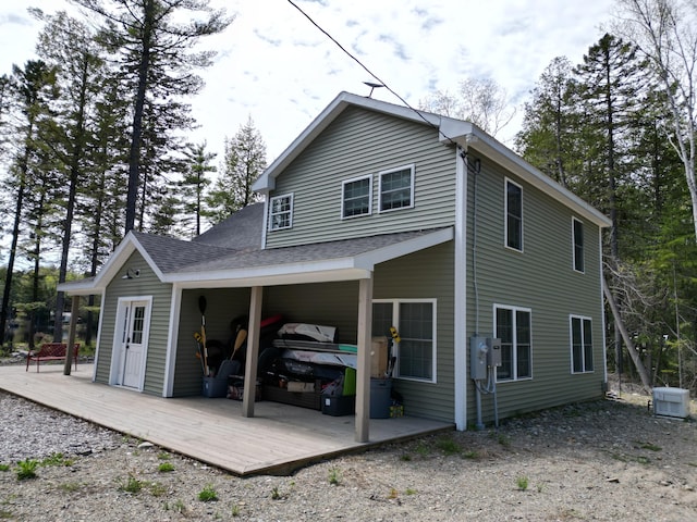 rear view of property with a wooden deck and a shingled roof