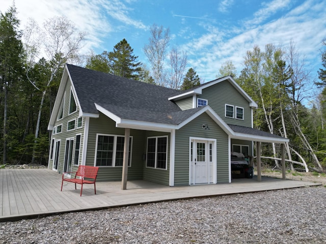 back of house with roof with shingles and a wooden deck
