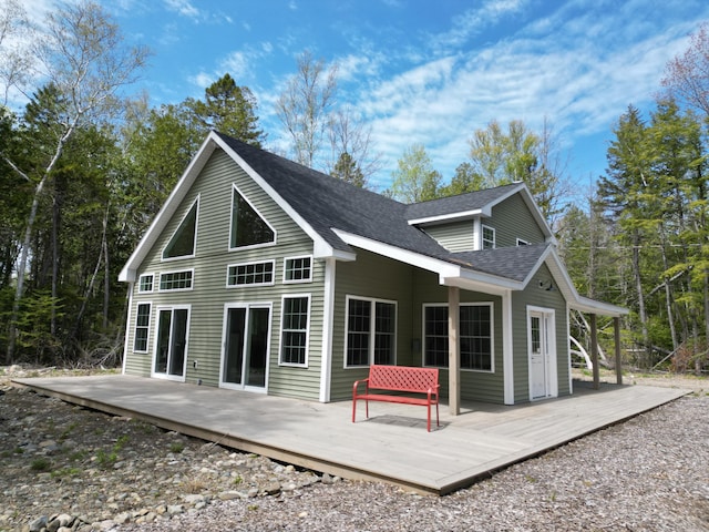 back of house with roof with shingles and a wooden deck