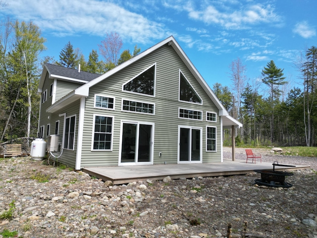 back of property with an outdoor fire pit and a deck
